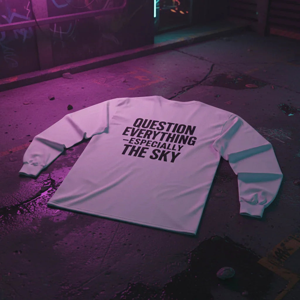 White long sleeve shirt with 'Question Everything Especially The Sky' text, on urban street at night