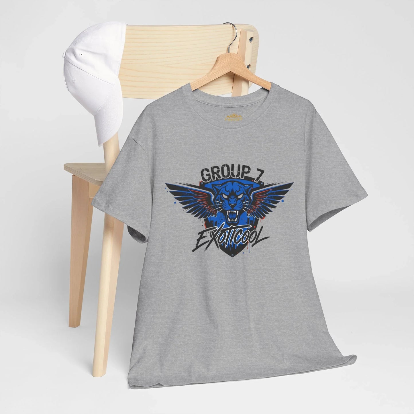 Gray t-shirt with Group 7 Exotikool panther graphic on hanger, white cap on wooden chair