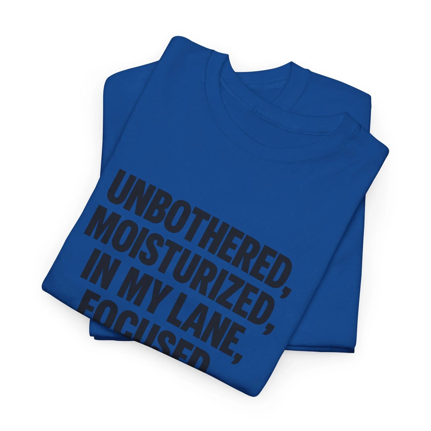 Folded blue t-shirt with bold black text reading 'UNBOTHERED, MOISTURIZED, IN MY LANE, FOCUSED'.